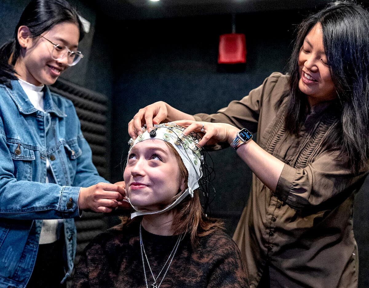 Researchers fitting an EEG cap on a study participant